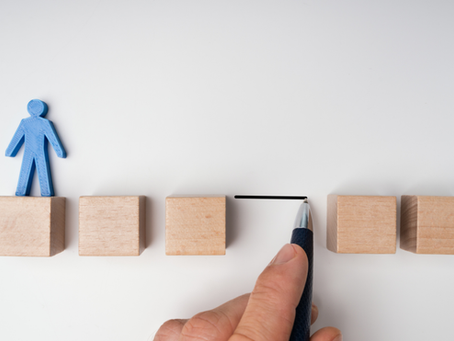 Blue figure on wooden blocks while a hand draws a line between them on a white background.