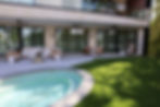 Curved swimming pool and spa area lined with tropical plants and vibrant synthetic turf for a low-maintenance, luxury look in florida