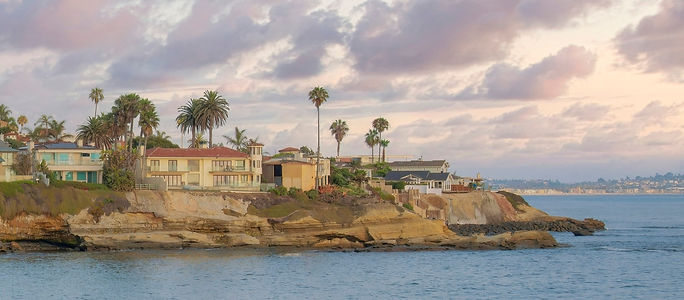 Square Puffy clouds at sunset La Jolla rocky coastal lines with beach front homes in Calif
