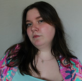 self portrait; neutral expression with hair flowing down, wearing colorful shirt