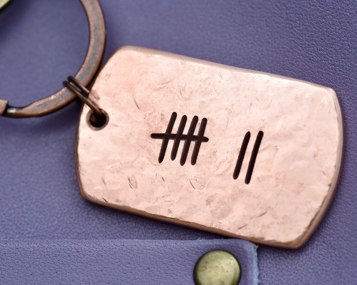 Hand-hammered solid copper keychain engraved with 7 tally marks to mark a 7th wedding anniversary.