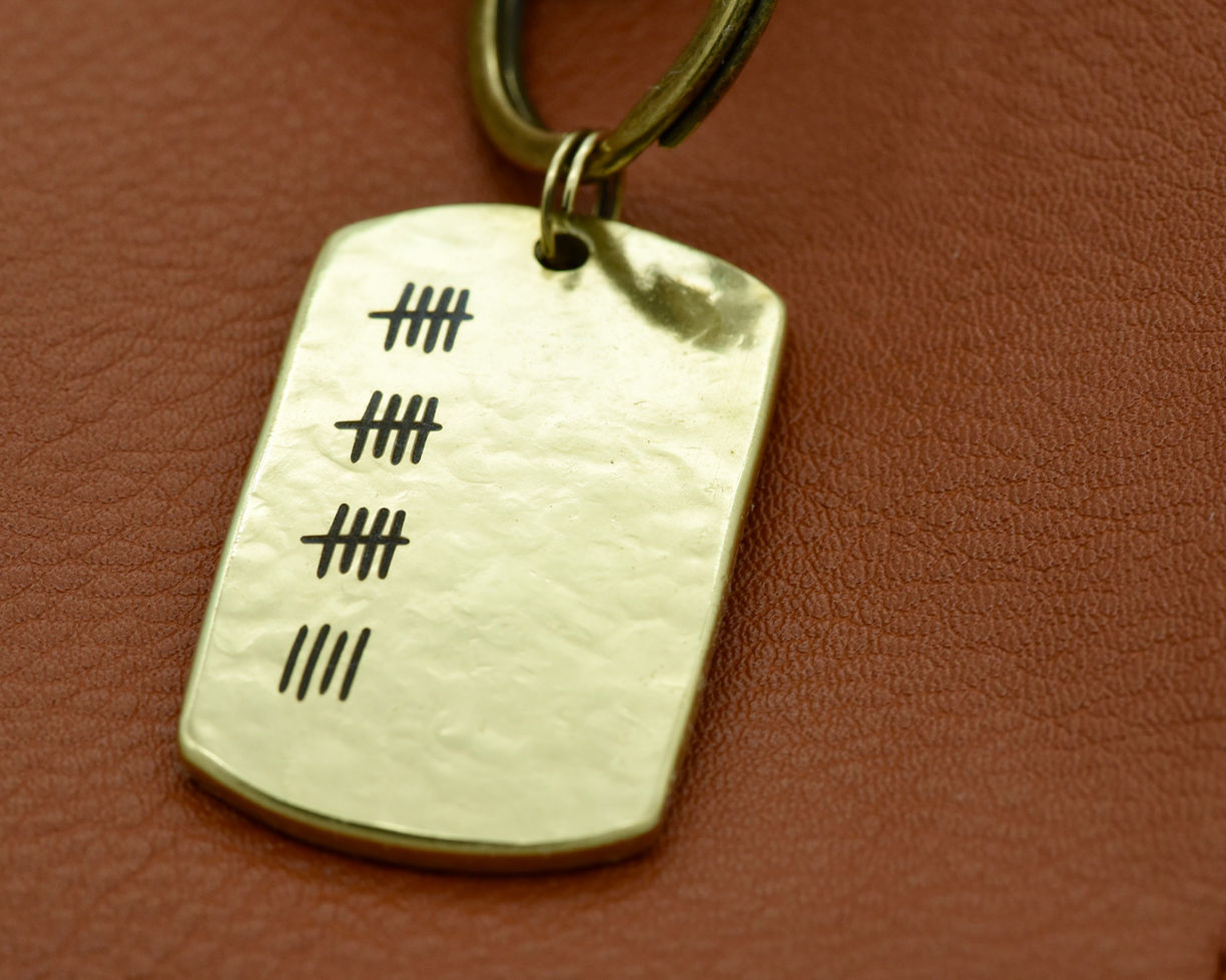 Hand-hammered bronze anniversary keychain featuring 19 tally marks symbolizing years of love and partnership.