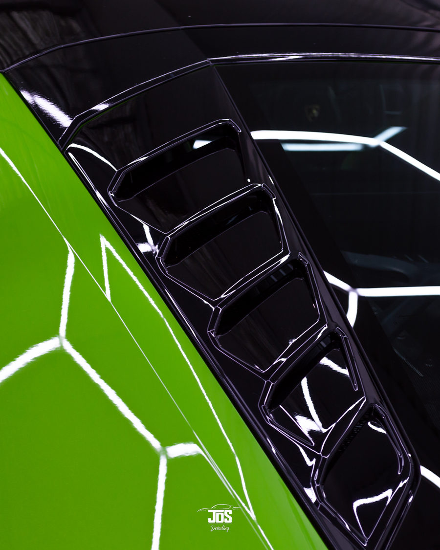 Green supercar panel with a deep, glossy coated finish reflecting hexagon lights