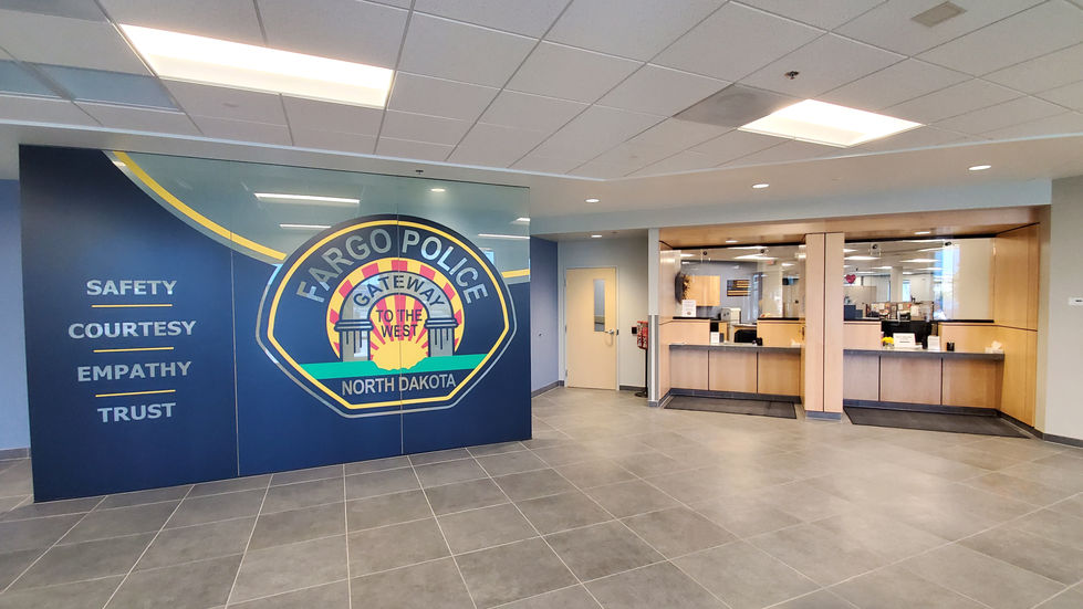 Lobby with a frosted glass partition wall and a police motto vinyl graphic.