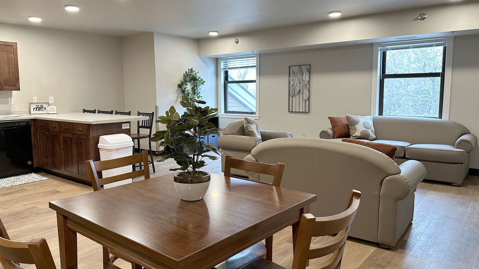 Apartment unit’s kitchen, dining, and living room with views to the nature outside. 