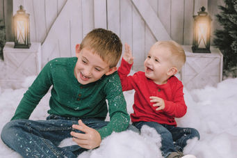 Two young boys laughing in winter scene; one is wearing red.