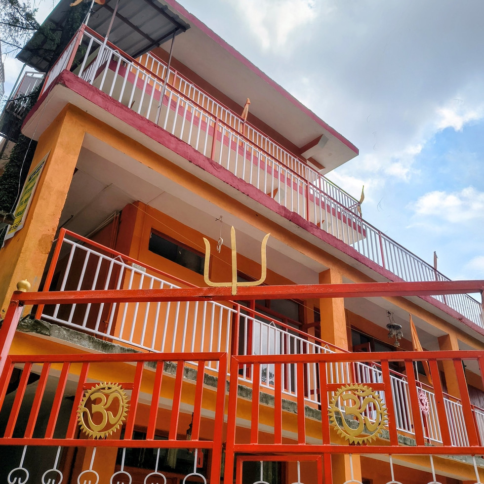 Yoga students practicing meditation and yoga teacher training at Om Yoga Ashram with panoramic Himalayan mountain views in Dharamshala, India.