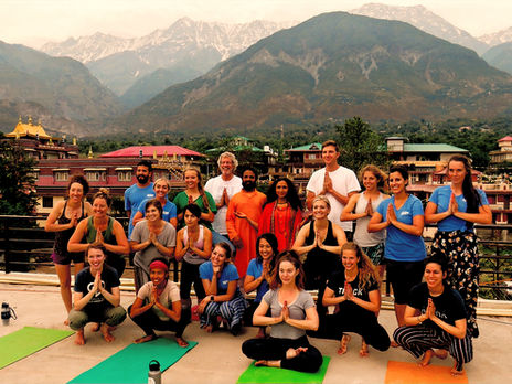 Yoga teacher training session in the Himalayas with students practicing asanas surrounded by serene mountain views and natural landscapes.