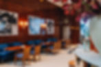 Dining area with tables and chairs in Cipriani restaurant, featuring flower arrangements and large portraits on the wall