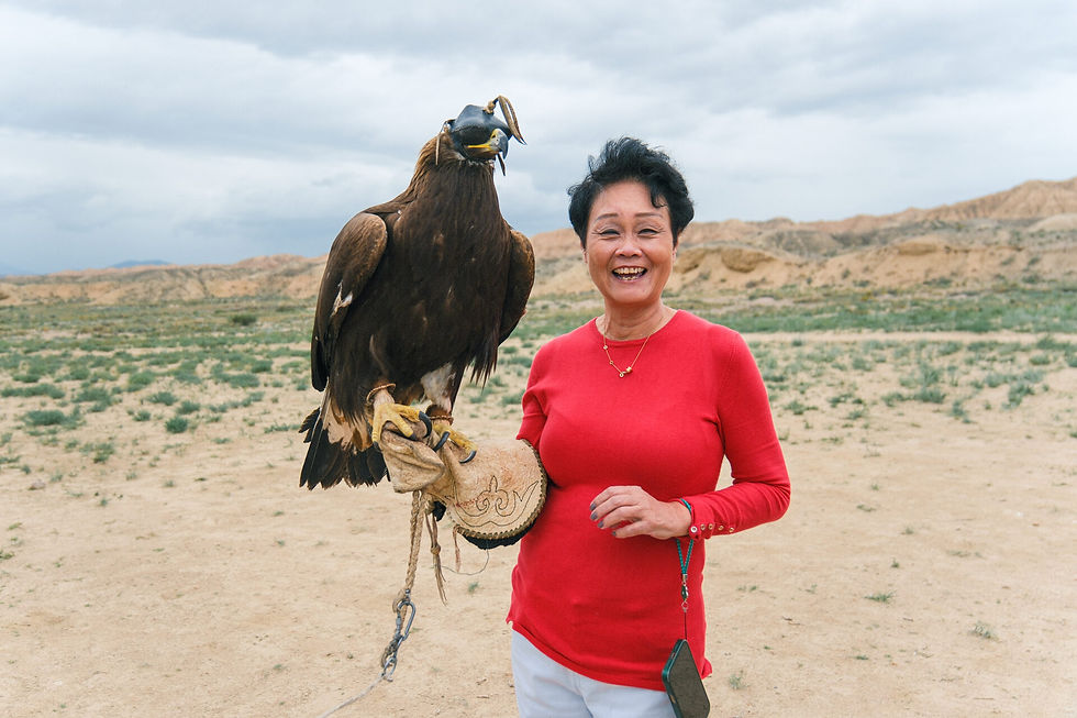 Kamakino Travel - Woman holding a golden eagle in a desert landscape in Kyrgyzstan