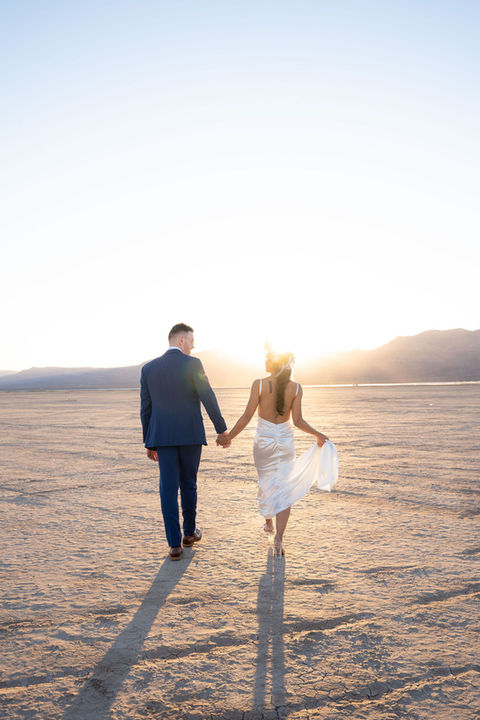 Couple holding hands walking towards the sunset; Dry Lake Bed Ceremony; wedding day TIMELESS CONNECTION