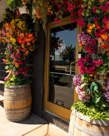 Entrance with flowers and barrel planters. Wine Garden Ceremony. Restaurant exterior with floral decor.