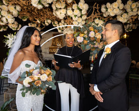 Bride and groom at ceremony officiated by woman with book. Wine Garden Ceremony.