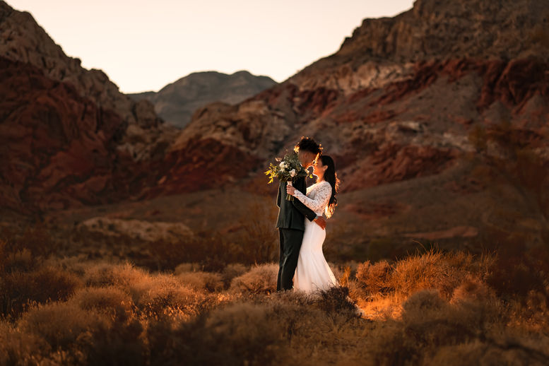 Couple embraces during outdoor wedding ceremony, with mountains in the background. TIMELESS CONNECTION