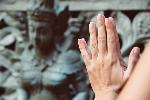Palms in a praying gesture. Namaste hands with an ethnic statue on the background..jpg