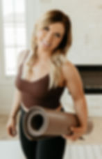 a woman smiling holding a yoga mat.