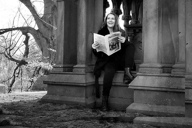 Genevieve Manion holding a newspaper and smiling in a grave yard.