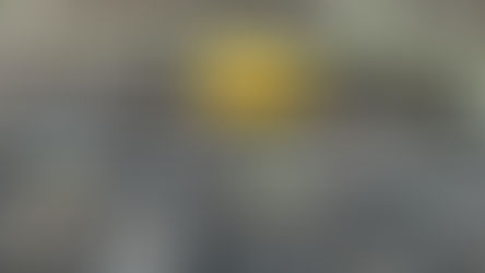 A close-up photograph taken at a residence in New Albany, Ohio, showing a brick foundation wall meeting a bed of dark wood mulch. A yellow arrow points to a vertical gap between two bricks, known as a weep hole, which is situated at the mulch line. The image demonstrates how low-set weep holes and adjacent organic mulch create an entry path for pests into the building's interior.