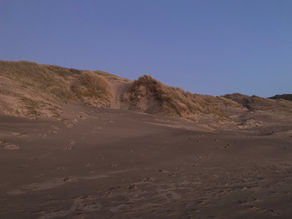 A mans face in the sand dunes at Harlech
