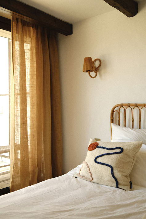 Chambre aux rideaux de lin doré, tête de lit de cannage, penthouse d'Ibiza