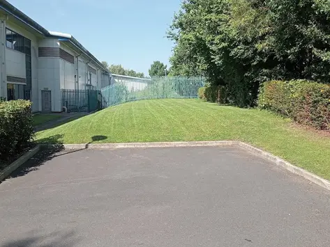 Maintained grass verge alongside a commercial site access road