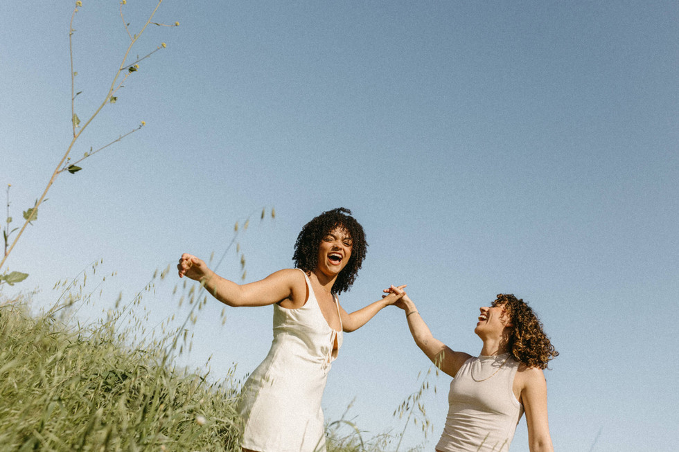 candid photo of lesbian couple laughing in field in los angeles engagement session