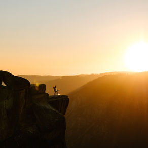 A couple embraces on the edge of a cliff at Taft Point in Yosemite during their sunset elopement, with breathtaking views of Yosemite Valley in the background