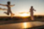 Two brides jumping on a trampoline during golden hour at a wedding at Nxwhere California in Joshua Tree, photographed by a Joshua Tree wedding photographer