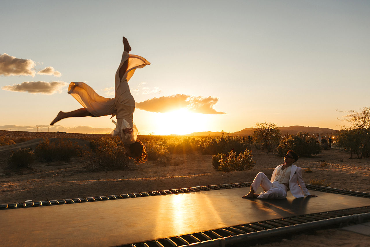 brides jumping on trampoline at nxwhere california during golden hour