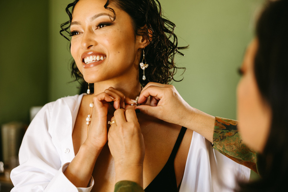 mom helping bride with short curly hair put on her necklace