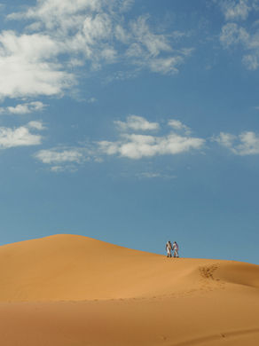 lesbian couple walking atop dunes at their elopement at coral pink sand dunes state park