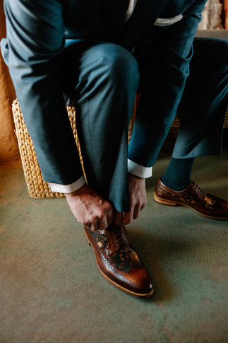 groom tying unique leather shoes at wedding at sacred sands in joshua tree