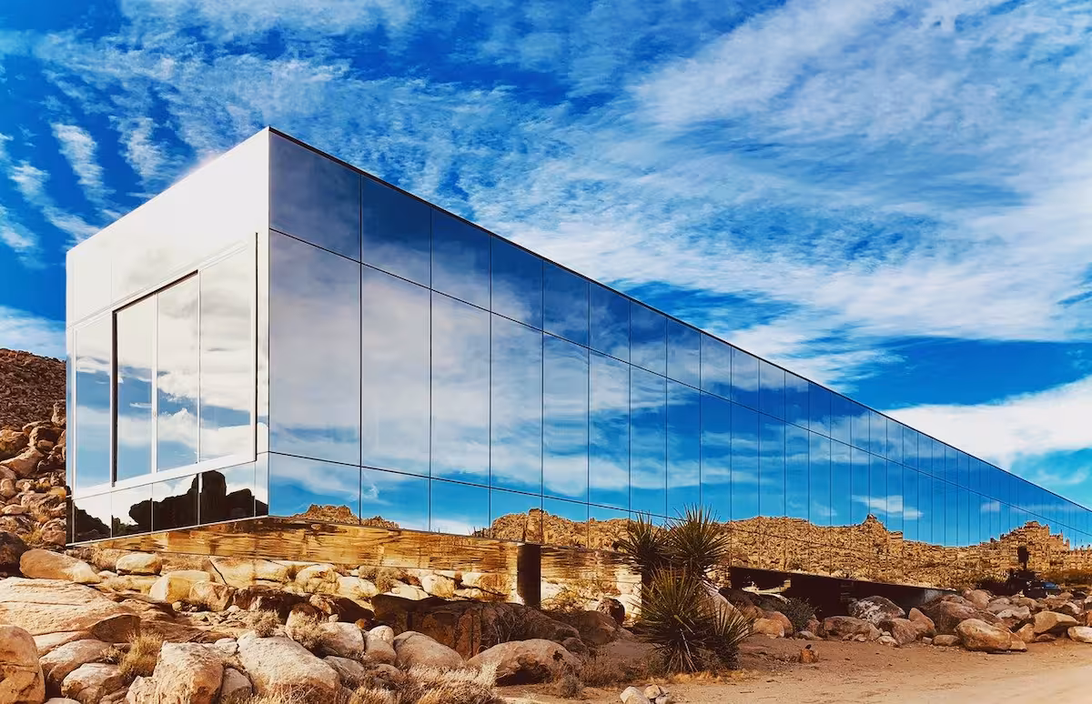 Invisible House wedding venue in Joshua Tree, featuring mirrored glass walls reflecting the desert landscape and blue sky