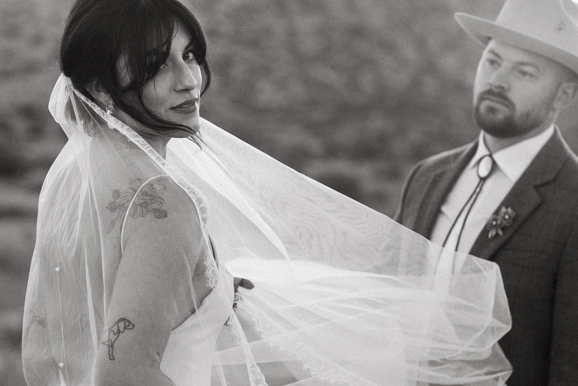 bride's veil blowing in the wind and groom looking at bride in joshua tree wedding