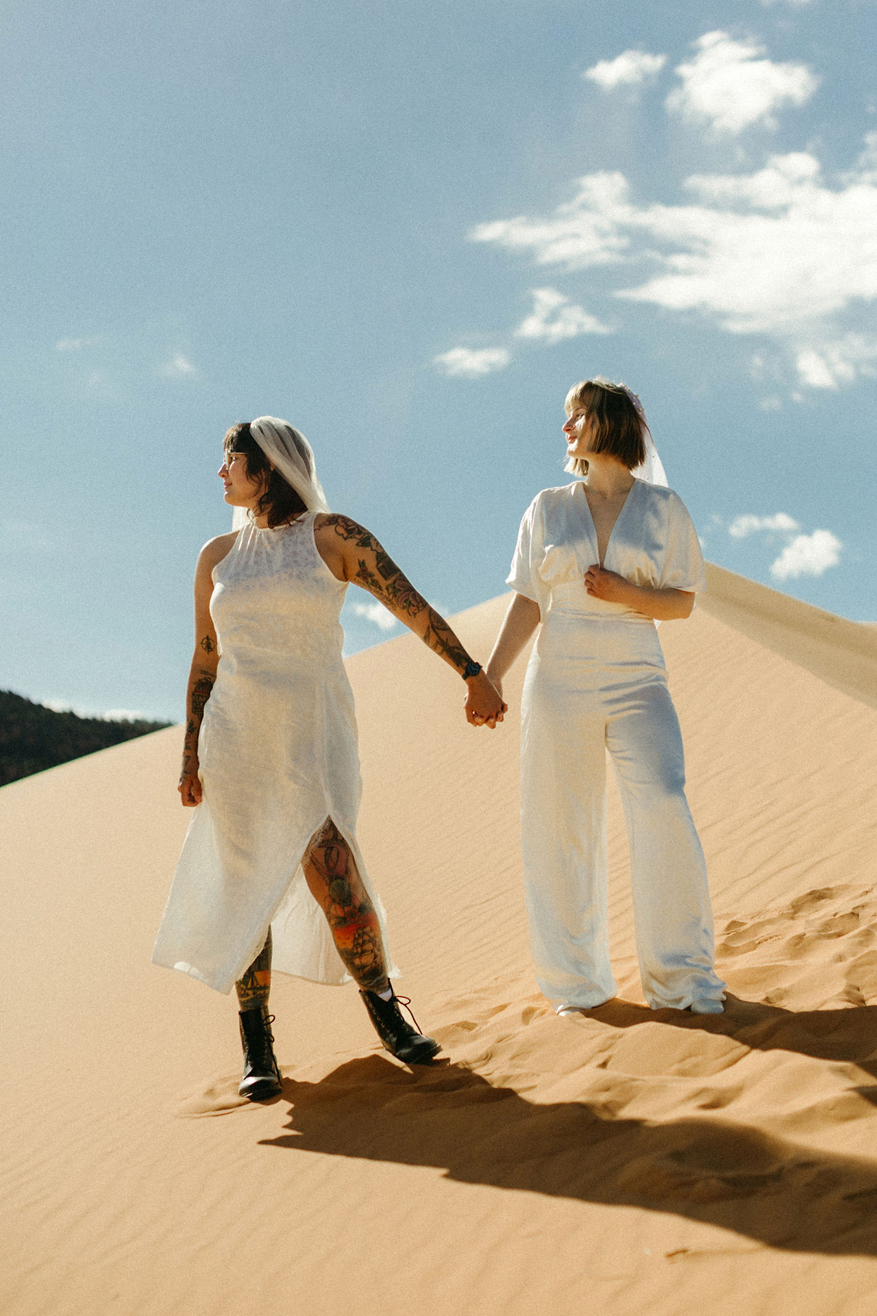 coral pink sand dunes state park lesbian elopement brides standing on sand dunes looking off into the distance