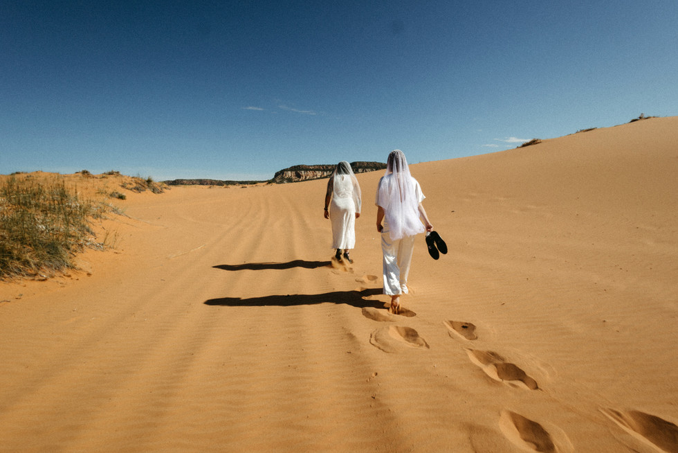 coral pink sand dunes state park lesbian elopement couple walking on sand dunes