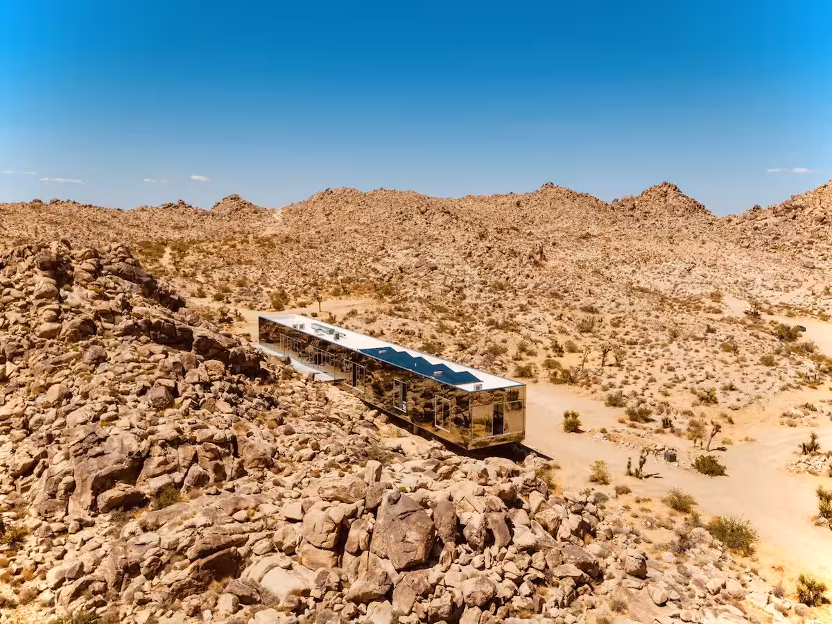 Invisible House wedding venue in Joshua Tree, featuring mirrored glass walls reflecting the desert landscape and blue sky.