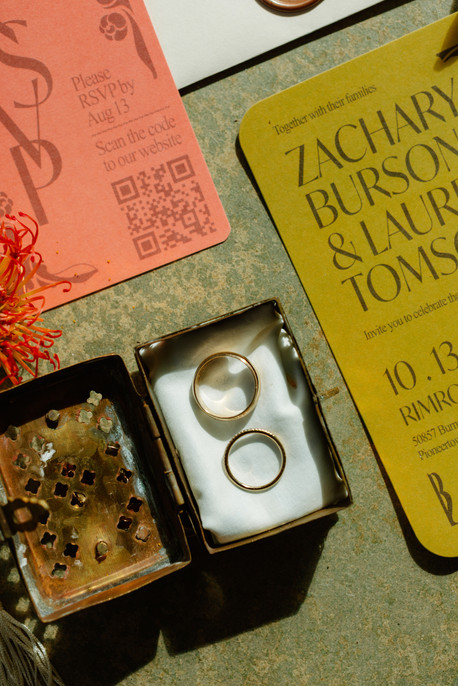 close up of gold rings in wedding invitation flatlay