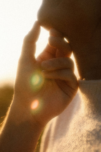 sunset engagement session closeup of guy's hand holding girl's chin with sun flares
