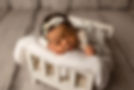 Newborn sleeping on tiny bed with little bear