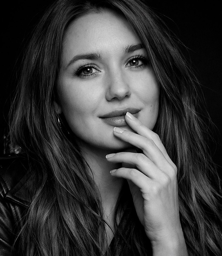 Primer plano de mujer sonriendo, mano en mejilla, pelo largo y oscuro.