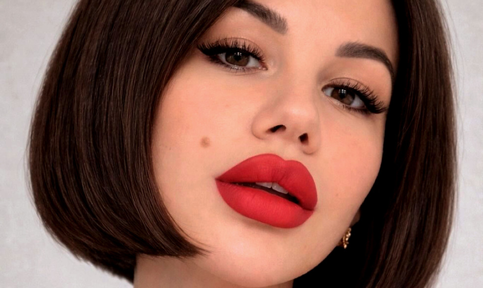 Mujer con cabello bob oscuro y labios rojos vibrantes.
