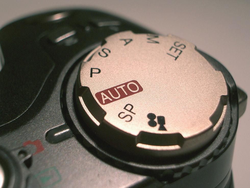 lose-up of a camera mode dial showing settings like "AUTO," "SP," and "M."