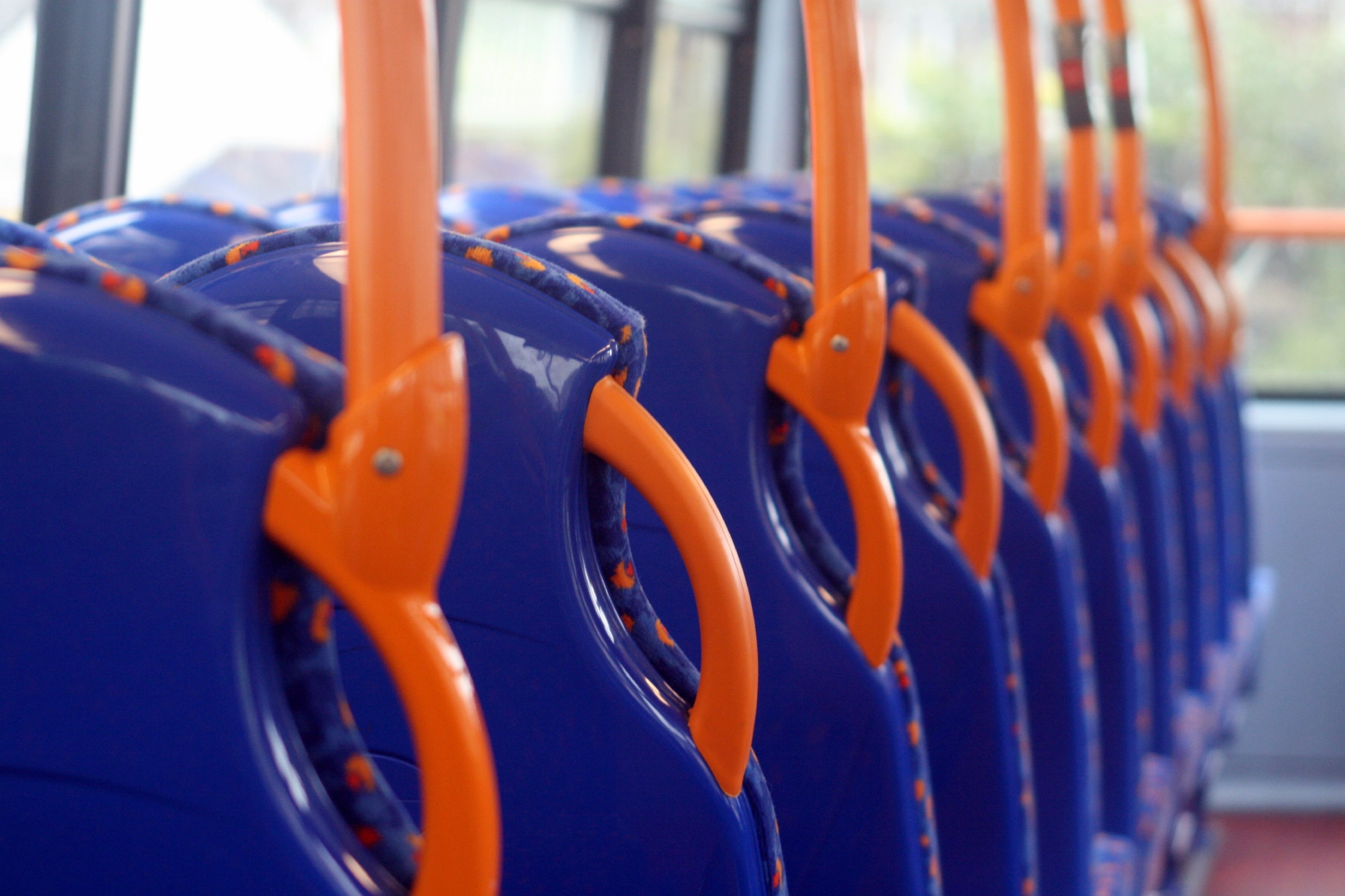 Colorful bus interior featuring blue seats with orange armrests arranged in a row