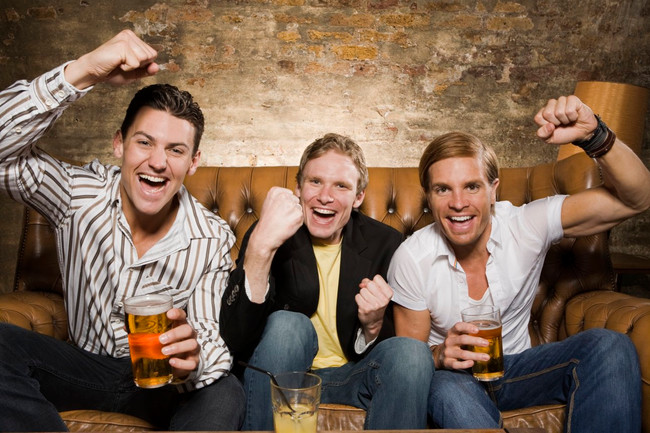 Three men cheering on a couch 