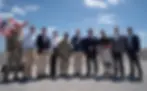 Group of people, some in military attire, stand smiling for a photo at the EAA Reservoir construction site for the announcement of more than $2 billion in funding in April 2026. Flags in the background, construction crane visible under a blue sky. From left to right: USACE COL Brandon Bowman; SFWMD Executive Director Drew Bartlett; The Everglades Foundation CEO Eric Eikenberg; Florida Department of Environmental Protection Secretary Alexis Lambert; USACE MG Jason Kelly; Assistant Secretary of the Army for Civil Works Adam Telle; Florida Governor Ron DeSantis; U.S. Representative Brian Mast; U.S. Representative Mario Diaz-Balart; Deputy Assistant Administrator for EPA Office of Water Dr. Wesley Brooks.