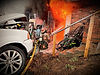 Firefighter extinguishing a building fire near a white vehicle