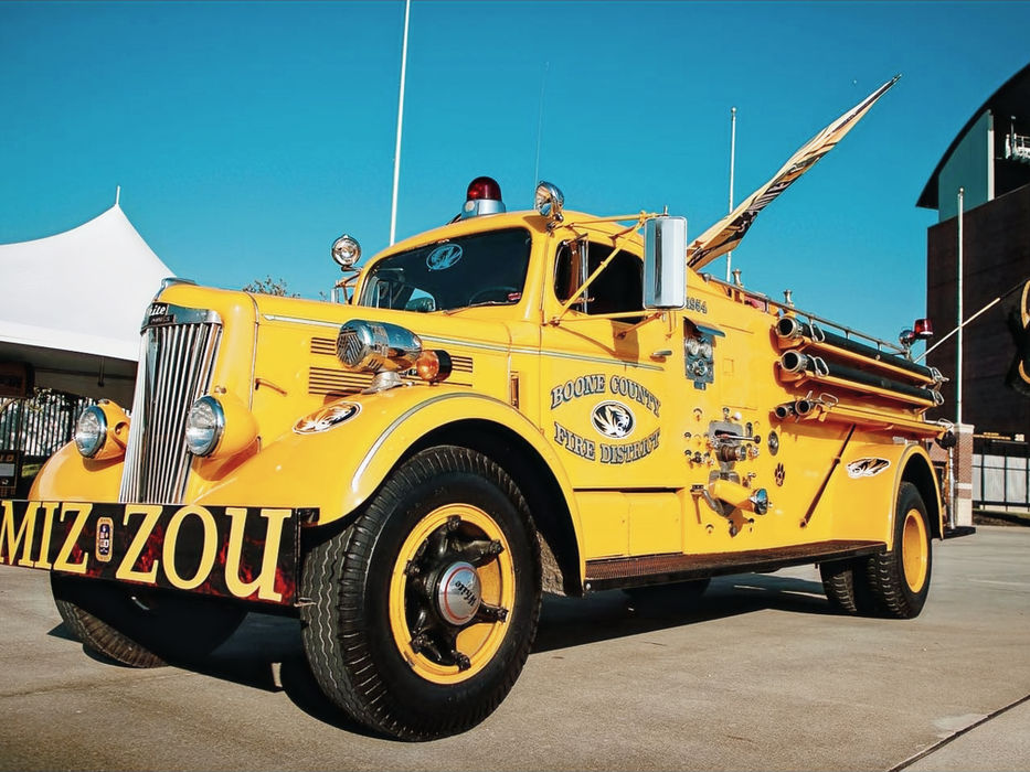 Yellow Mizzou vintage fire truck at a public event.