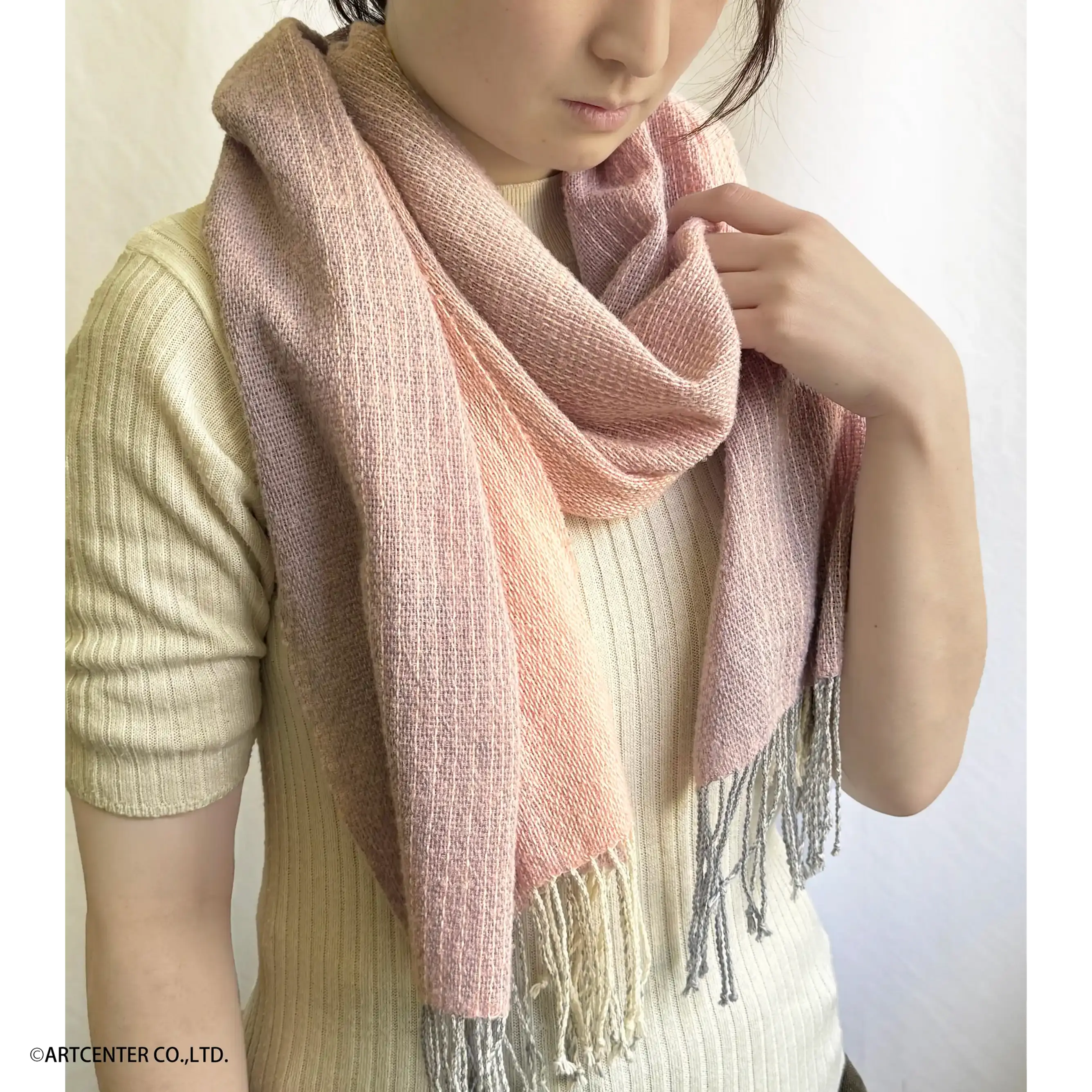 手織り糸キット「かすみグラデーションショール(ピンク)」の完成イメージ。半袖の白いニットを身につけた女性が薄いピンク色のショールを首に巻いている
