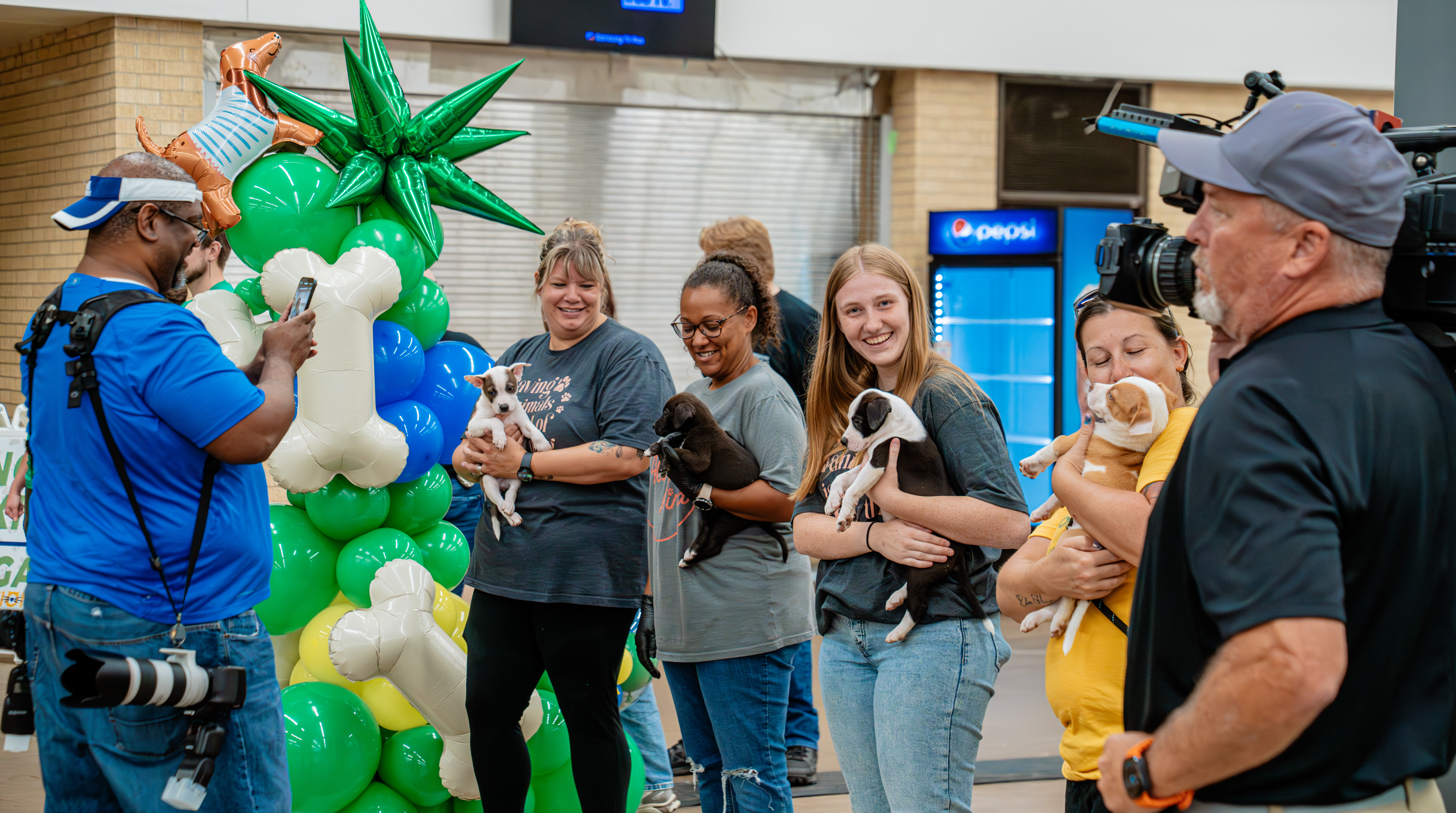 Staff and volunteers holding adoptable puppies at HSNT's MEGA Adoption Event